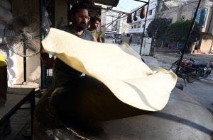 A vendor busy preparing large Manda Roti (Rumali Roti) and Samosa Patti at his roadside setup in Ghori Town.