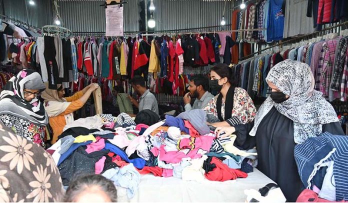 Women busy in selecting and purchasing old warm clothes at weekly bazaar in the Federal Capital