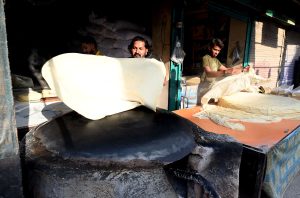 A vendor busy preparing large Manda Roti (Rumali Roti) and Samosa Patti at his roadside setup in Ghori Town.