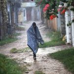 A man covers himself with a shawl to protect from rain in the Federal Capital