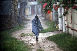 A man covers himself with a shawl to protect from rain in the Federal Capital