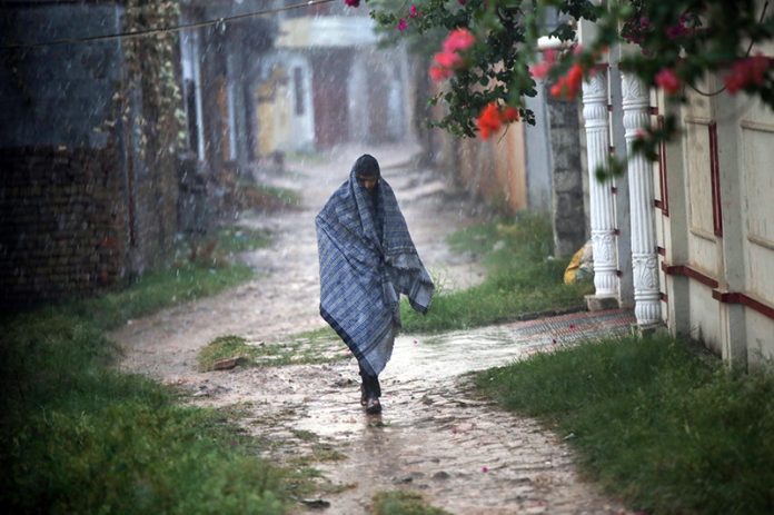 A man covers himself with a shawl to protect from rain in the Federal Capital
