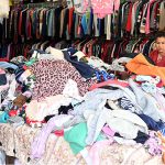 Woman selecting and purchasing second hand warm clothes and different winter stuff from the vendor at weekly bazar at Peshawar morr in the Federal Capital