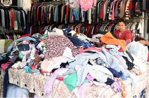 Woman selecting and purchasing second hand warm clothes and different winter stuff from the vendor at weekly bazar at Peshawar morr in the Federal Capital