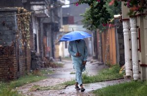 A man covers himself with a shawl to protect from rain in the Federal Capital