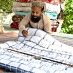 A worker stitches a quilt for sell in preparation of winter season at his workplace in the Federal Capital