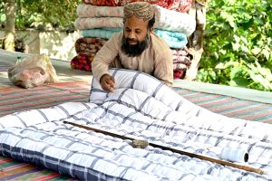 A worker stitches a quilt for sell in preparation of winter season at his workplace in the Federal Capital
