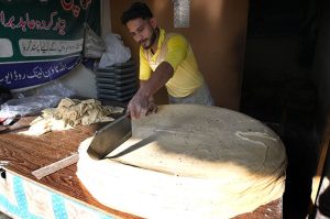 A vendor busy preparing large Manda Roti (Rumali Roti) and Samosa Patti at his roadside setup in Ghori Town.