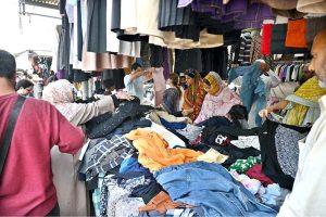 Women busy in selecting and purchasing old warm clothes at weekly bazaar in the Federal Capital