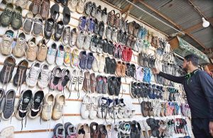 A youngster selecting old shoes from roadside setup near Khushab Road.