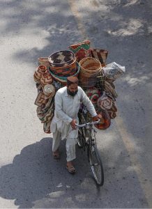 A vendor selling beautiful traditional handcrafted kitchen items on his bicycle at the roadside