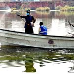 Cantonment Board Hyderabad workers busy spraying anti-dengue chemicals on stagnant water while sitting on a boat at the football ground outside Alamgir Road during the malaria and anti-dengue spray campaign