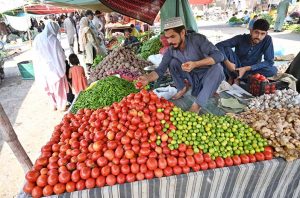 Woman purchasing vegetables from vendor at weekly bazaar, I-9/4 in the Federal Capital.