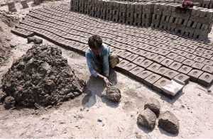 A young labourer prepares clay for brick-making at a local kiln, symbolizing the tireless human effort behind Larkana’s growing infrastructure
