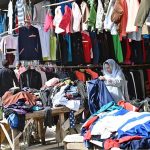 Women busy selecting and purchasing second hand warm clothes from vendor in weekly bazaar at I-9/4