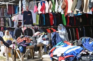 Women busy selecting and purchasing second hand warm clothes from vendor in weekly bazaar at I-9/4