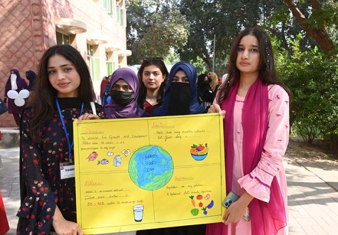 Students hold placards during an event organized by the Institute of Food Science and Nutrition at the University of Sargodha in connection with World Food Day
