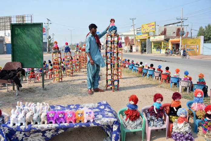 A vendor displaying dolls to attract customers at his roadside setup A vendor displaying dolls to attract customers at his roadside setup