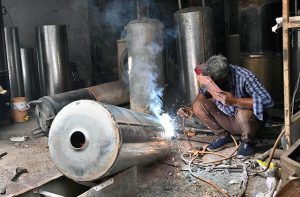 A worker repairing a water geyser in preparation of winter at his workplace in the city.