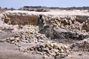 A young labourer prepares clay for brick-making at a local kiln, symbolizing the tireless human effort behind Larkana’s growing infrastructure