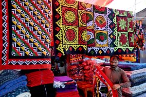 A vendor displaying handmade bed sheets to attract the customers at Jilis Bazaar