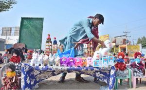 A vendor arranging colorful stuffed cats, rabbits and dolls to attract the customers at his roadside stall near Rajapur.