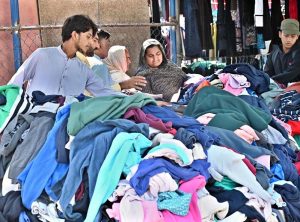 Women busy selecting and purchasing second hand warm clothes from vendor in weekly bazaar at I-9/4