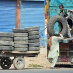 Labourers busy loading old tyres onto a delivery truck at Muzaffargarh Road