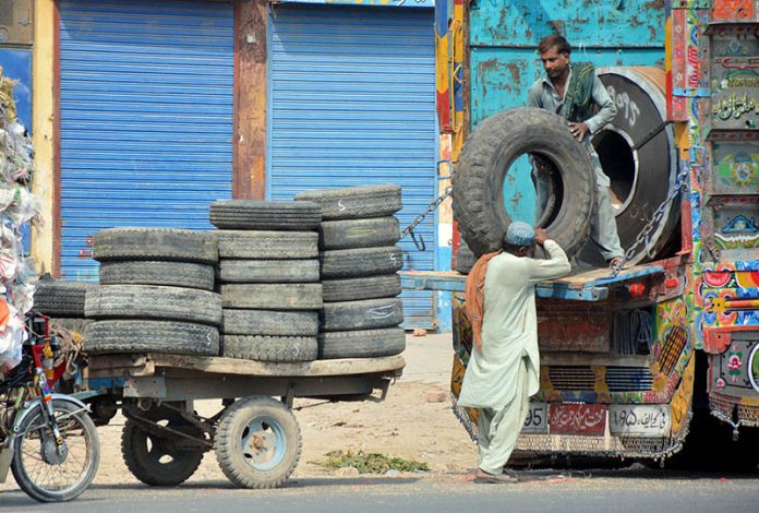 Labourers busy loading old tyres onto a delivery truck at Muzaffargarh Road Labourers busy loading old tyres onto a delivery truck at Muzaffargarh Road