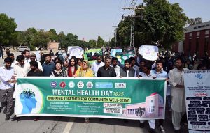 Students of the Department of Psychology and Counseling Center holding a banner during an awareness walk organized on the occasion of World Mental Health Day 2025 at the University of Sargodha.
