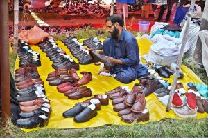 Women busy selecting and purchasing second hand warm clothes from vendor in weekly bazaar at I-9/4