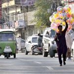 A street hawker wandering along the roadside to sell colourful balloons to earn for livelihood at satellite market