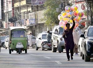 A street hawker wandering along the roadside to sell colourful balloons to earn for livelihood at satellite market