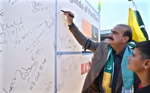 Patron-in-Chief Pakistan Sweet Homes Zamurd Khan signing on the board during solidarity walk regarding Kashmir Black Day from Foreign Office to D-Chowk.