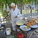 An old vendor is preparing traditional food item for customers at his roadside setup in front of Zulfiqar Bagh