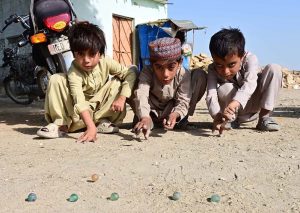 Children play marbles a traditional game to spend their leisure time in Latifabad