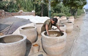 An artisan busy preparing traditional oven (tandoor) at Railway Chowk.