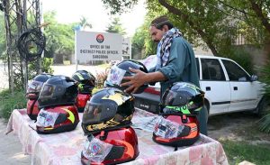 A local vendor is displaying motorcycle helmet on his cart to attract the customers at DPO office Chowk.