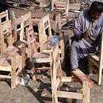 A carpenter is busy making small wooden chairs for children at his workplace near Miro Khan Road