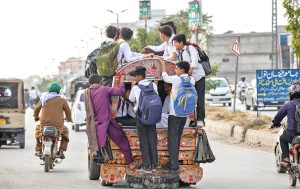 A view of an overloaded school van with students hanging outside, posing a serious risk of mishap. APP/MAF/TZD/SSH