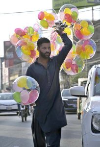 A street hawker wandering along the roadside to sell colourful balloons to earn for livelihood at satellite market
