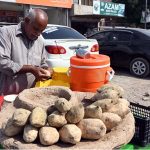A vendor selling sweet potato to attract the customers at his roadside setup.