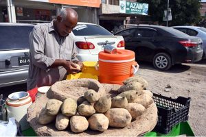 A vendor selling sweet potato to attract the customers at his roadside setup.