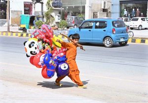 A street hawker wandering along the roadside to sell colourful balloons to earn for livelihood at satellite market