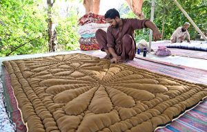 A worker busy in stitching quilt for customers at his workplace G-7 Sector in the Federal Capital.