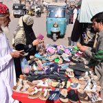 People selecting and purchasing old shoes and sandals from vendor at Cloth market road