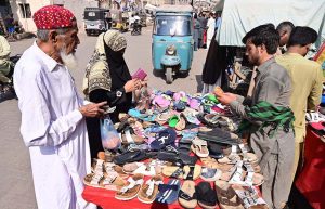 People selecting and purchasing old shoes and sandals from vendor at Cloth market road