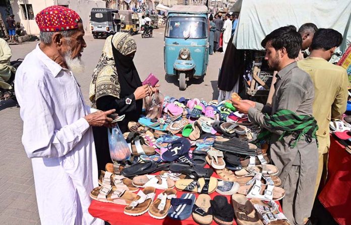 People selecting and purchasing old shoes and sandals from vendor at Cloth market road