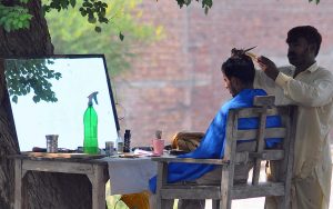 A barber trimming a customer’s hair at his roadside setup in the city.