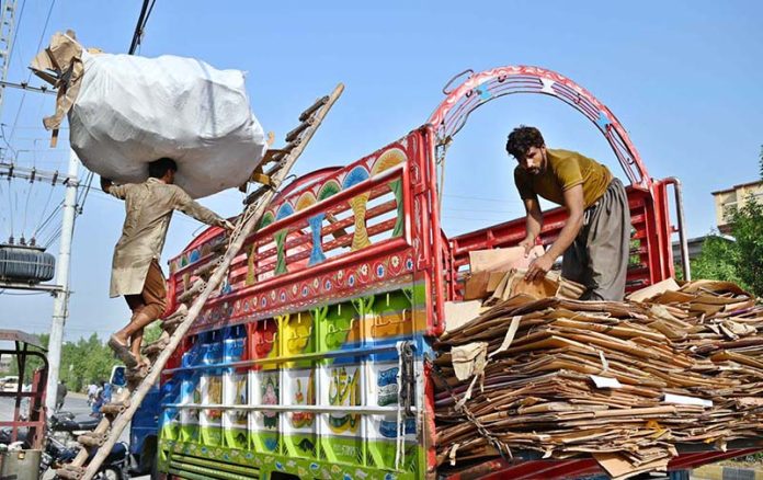 Laborers loading scrap on delivery truck